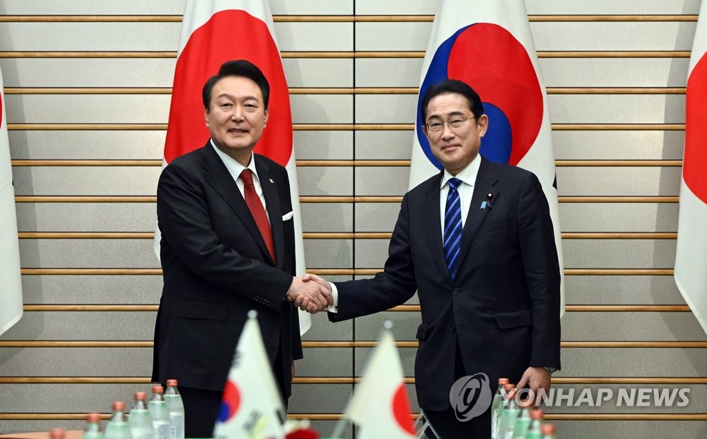 资料图片：3月16日，在位于东京的日本首相官邸，韩国总统尹锡悦（左）同日本首相岸田文雄举行首脑会谈。图为两位领导人在扩大会谈前握手合影。 韩联社