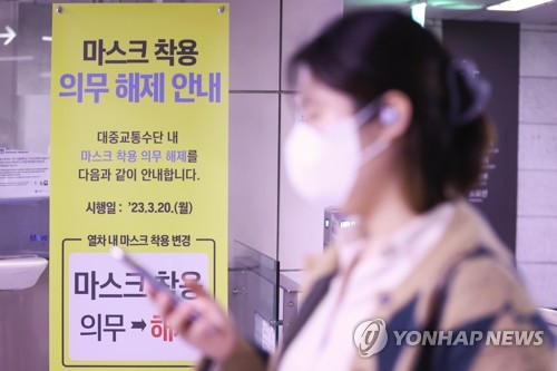 资料图片:首尔一地铁站摆出关于解除公共交通工具戴口罩义务的标牌,摄于3月19日。 韩联社