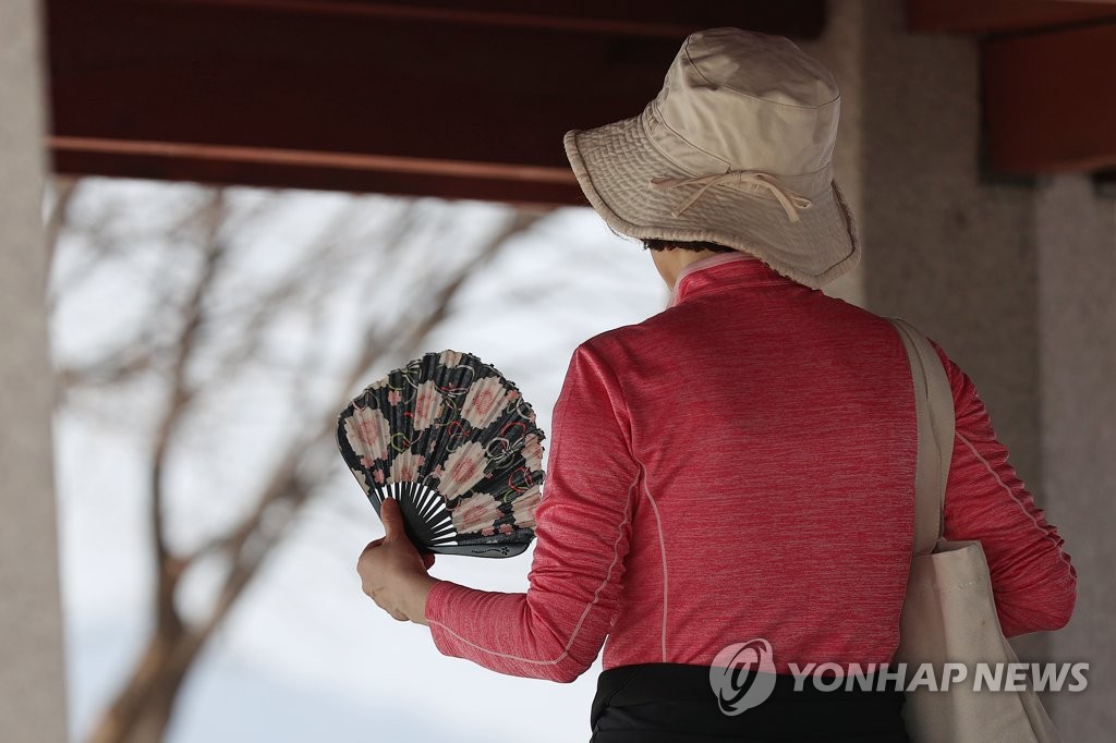 3月22日，全国各地气温上升，在首尔城东区的应峰山，市民已用起了扇子。 韩联社