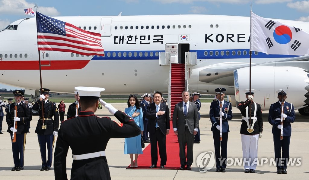 当地时间4月24日，在美国华盛顿，韩国总统尹锡悦（中）和夫人金建希（左）搭乘总统专机“空军一号”飞抵安德鲁斯空军基地。图为尹锡悦伉俪向国旗敬礼。 韩联社