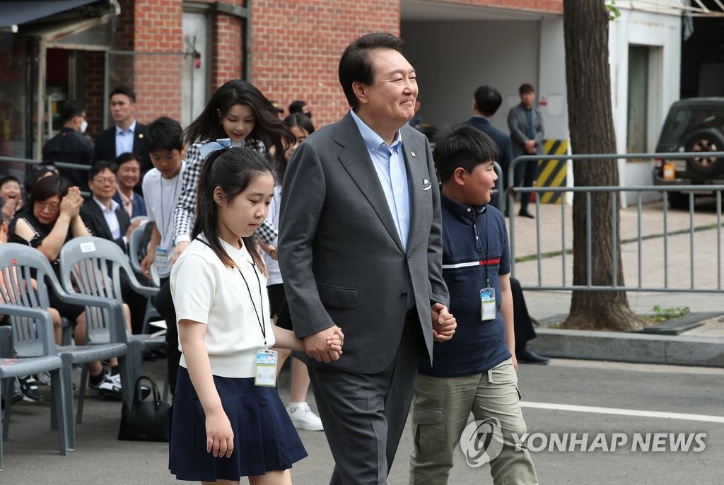 5月4日，龙山儿童庭院开放活动在首尔龙山总统府前院举行，图为总统尹锡悦和孩子们牵手入场。 韩联社/总统室通讯摄影记者团