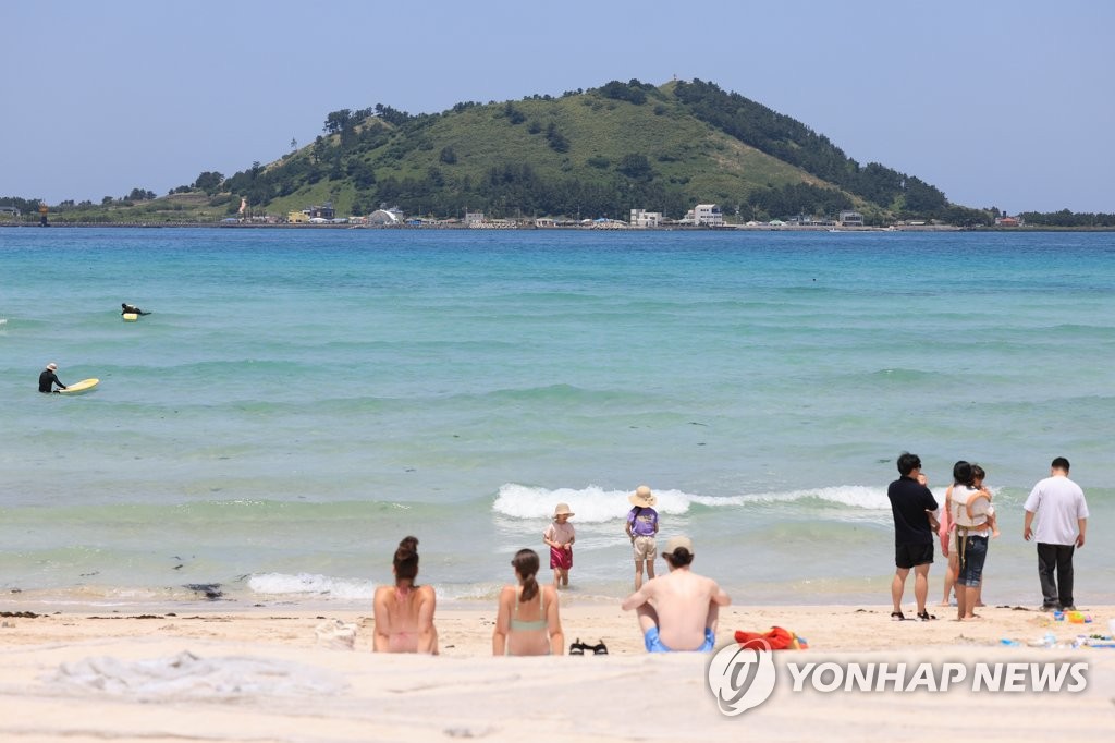资料图片：5月23日，在济州市翰林邑的挟才海水浴场，游客畅享夏日海滨的气息。 韩联社