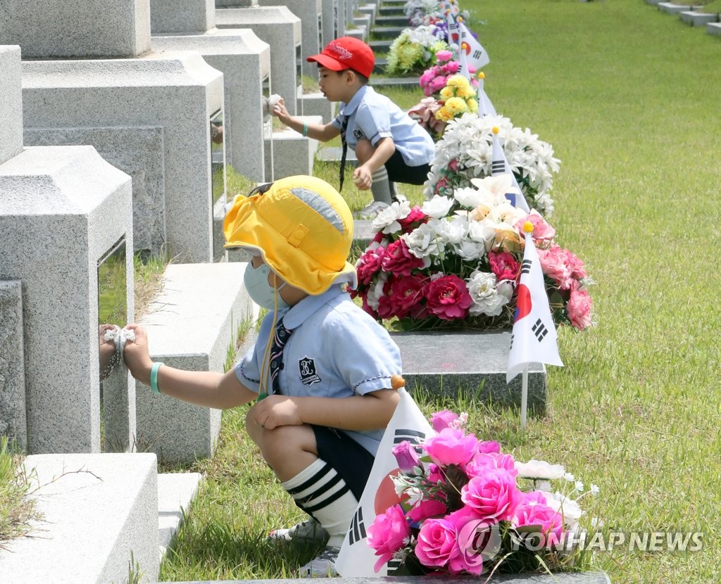 资料图片：6月2日，在国立大田显忠院，幼儿院的孩子们正在擦拭爱国志士的墓碑。 韩联社