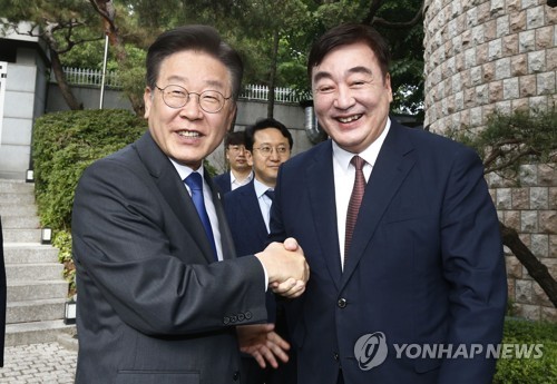 6月8日，在首尔市城北区的中国驻韩国大使官邸，韩国最大在野党共同民主党党首李在明（左）会见中国驻韩大使邢海明。图为两人亲切握手。 韩联社/国会摄影记者团