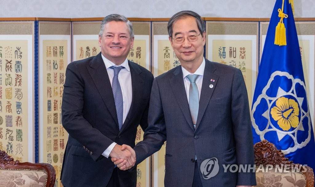 6月22日，在首尔钟路区的中央政府首尔办公楼，韩国国务总理韩悳洙（右）会见到访的全球视频服务平台奈飞（Netflix）的联席CEO泰德·萨兰多斯（Ted Sarandos）。图为二人亲切握手。 韩联社
