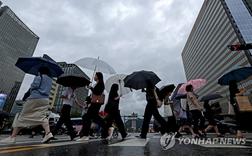 6月26日，在首尔光化门广场，市民们打着伞上班。由于中南部等地区的暴雨预警范围有所扩大，中央灾难安全对策本部当天凌晨3时启动一级应急响应。 韩联社