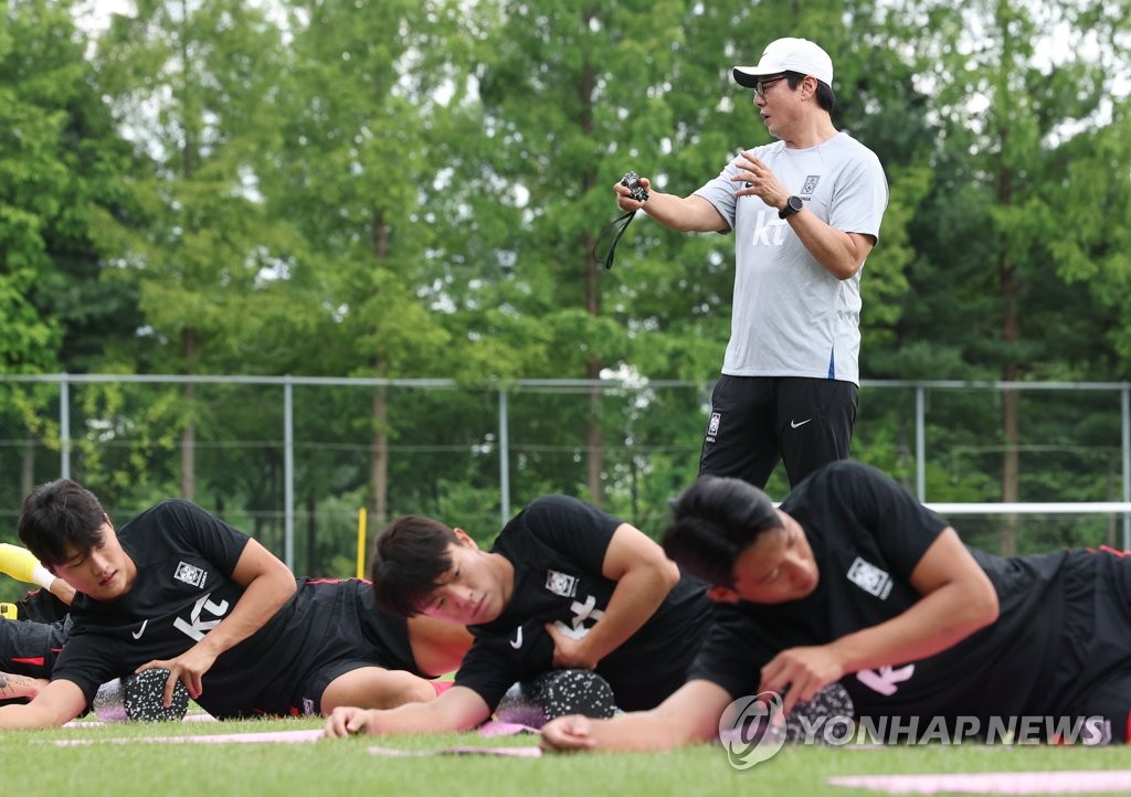 资料图片：7月25日，在坡州国家队训练中心，国脚们正在热身拉伸。 韩联社