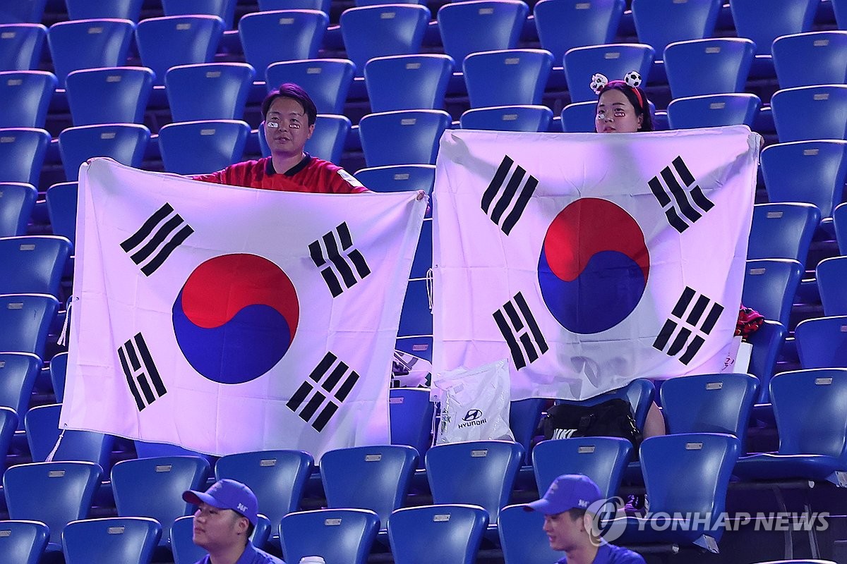 9月19日，在浙江省金华体育中心体育场，杭州亚运会男足小组赛E组第一轮韩国对阵科威特的比赛打响。图为韩国观众手举韩国国旗为国足加油助威。 韩联社