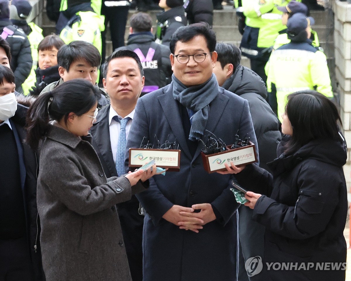 12月18日上午，在首尔瑞草区的首尔中央地方法院，涉嫌贿选的最大在野党共同民主党前党首宋永吉（居中）出庭接受逮捕必要性审查。图为宋永吉出庭前接受媒体采访。 韩联社