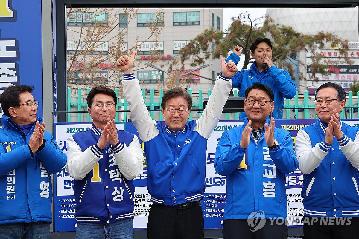 资料图片：3月28日，在仁川富平站，民主党党首李在明（中）举手致意。 韩联社