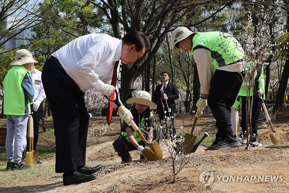 资料图片：4月5日，在釜山市江西区的鸣旨社区公园，韩国总统尹锡悦（左）出席植树日纪念活动并亲自种树。当天是韩国的植树日。 韩联社/总统室通讯摄影记者团