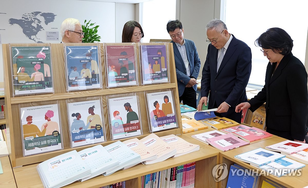 资料图片：4月12日，在首尔瑞草区的世宗学堂财团，文体部长官柳仁村（右二）观看展示中的韩语教材。 韩联社/文体部供图（图片严禁转载复制）