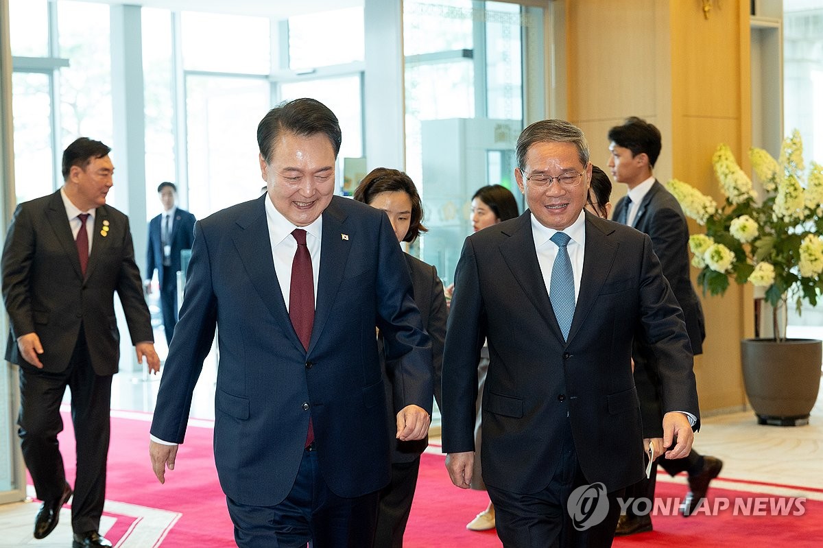 5月26日，在首尔龙山总统府，韩国总统尹锡悦（左）和中国国务院总理李强举行会谈。图为两国领导人走进会场。 韩联社/总统室供图（图片严禁转载复制）