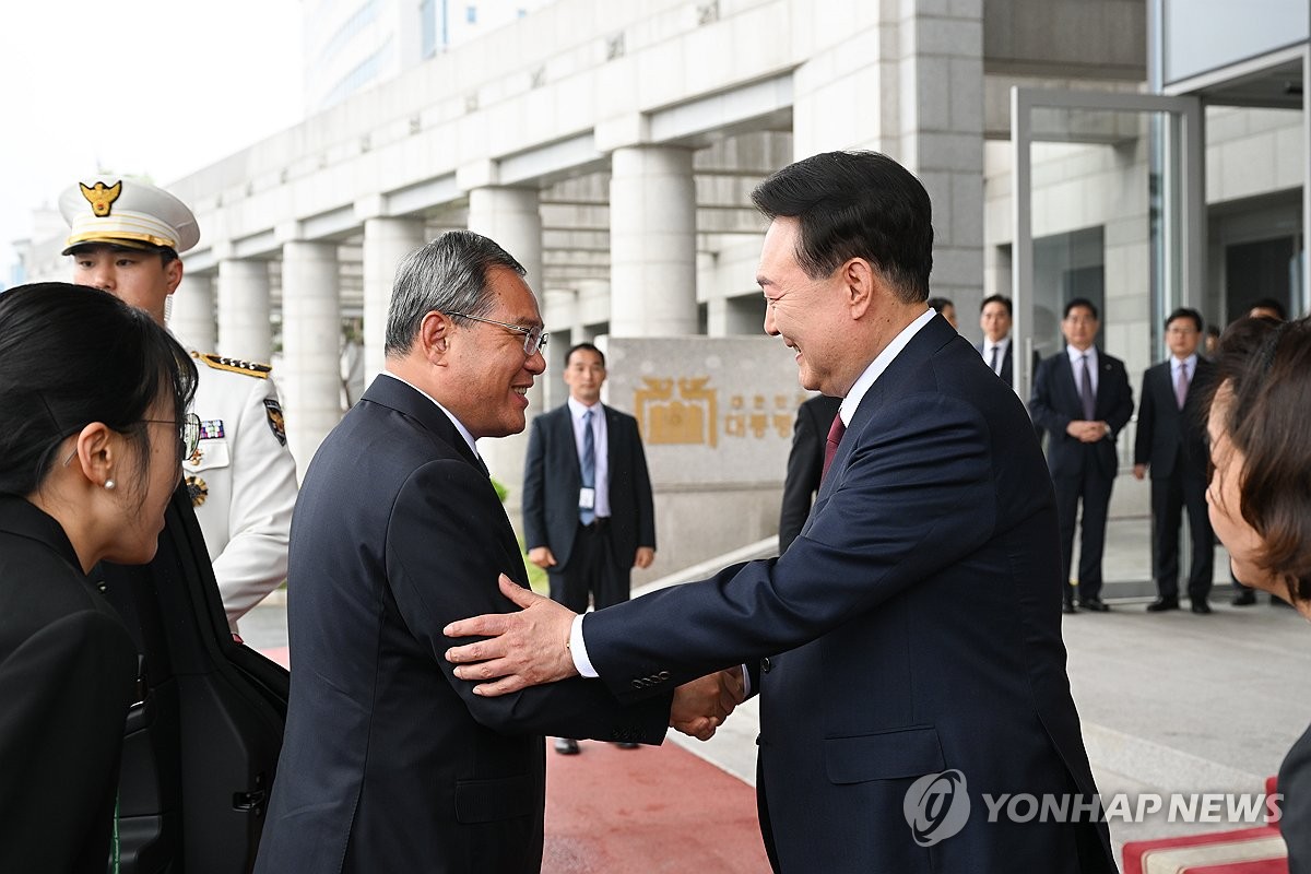 5月26日，在首尔龙山总统府，韩国总统尹锡悦（右）和中国国务院总理李强握手致意。 韩联社/总统室供图（图片严禁转载复制）