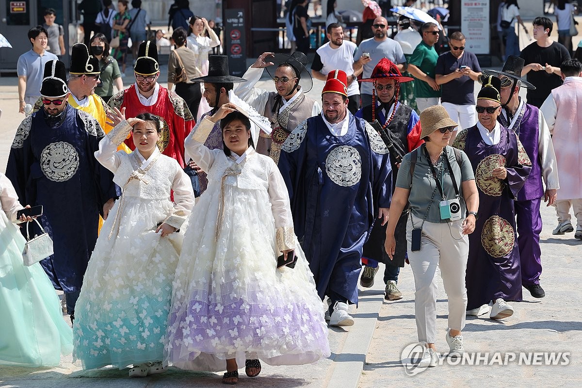 资料图片：6月13日，在首尔，外国游客穿韩服游景福宫。 韩联社