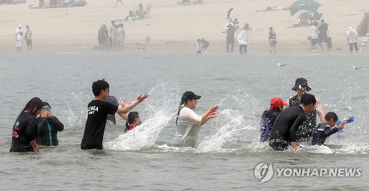 资料图片：6月16日，在仁川中区乙旺里海水浴场，游客们戏水消暑。 韩联社