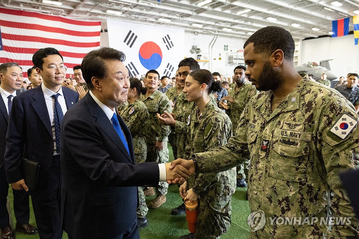 6月25日，在釜山海军作战基地，韩国总统尹锡悦（左）登上美国海军“西奥多·罗斯福”号核动力航空母舰，并勉励韩美官兵。 韩联社/总统室供图（图片严禁转载复制）