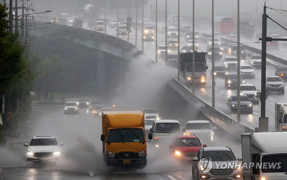 资料图片：7月8日，在光州市西区，倾盆大雨导致武珍大路多处积水，不少来往车辆溅起水浪。 韩联社