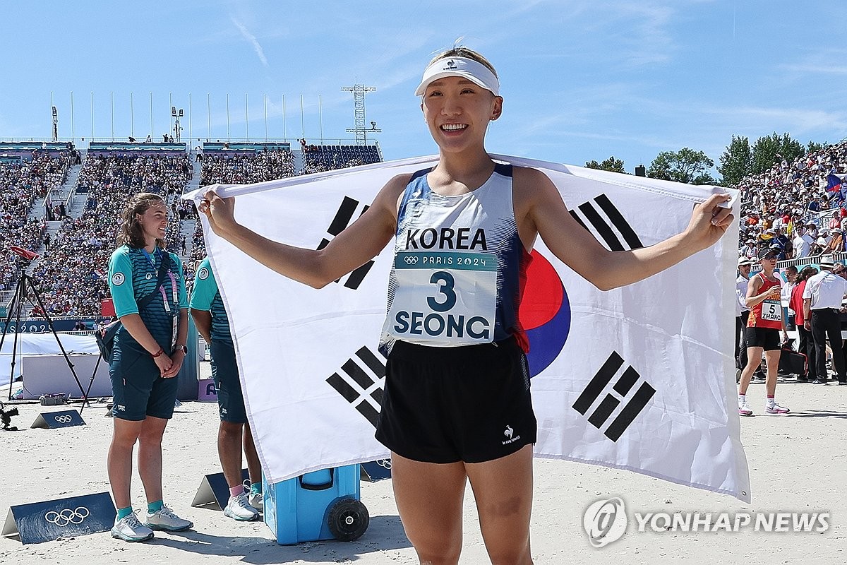 当地时间8月11日，在巴黎凡尔赛宫，韩国现代五项运动员成承民披上国旗庆祝摘铜。 韩联社/联合采访团