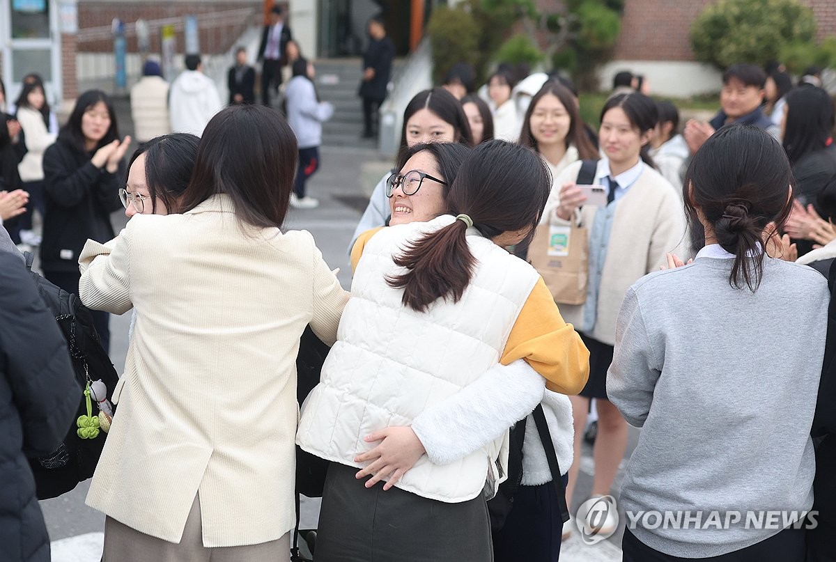 11月12日,在庆尚南道昌原市的一女子高中,老师们挨个拥抱高三学生,为其加油助威。 韩联社
